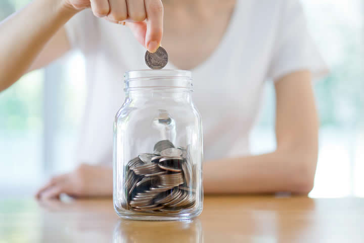 Woman Dropping Coins In Jar