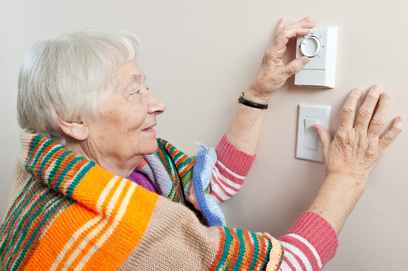 Senior Woman Adjusting Thermostat