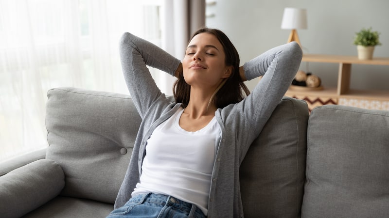 Woman With Arms Clasped Behind Head Relaxed On Couch