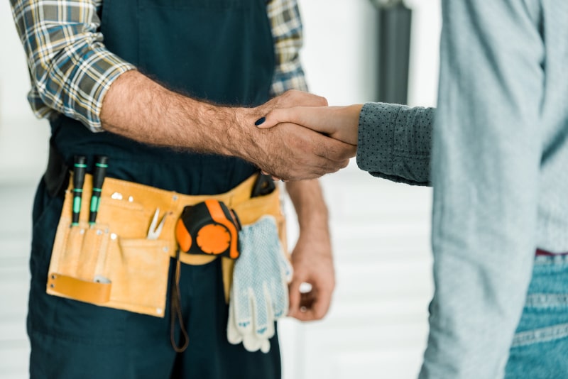 Handshake between contractor wearing tool belt and client